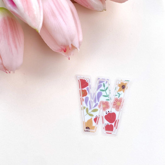 Decorative letter 'W' sticker with floral design on a light background with pink tulips.