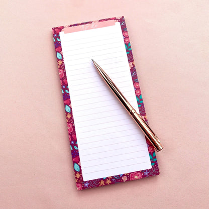 Floral-patterned notepad with a pen on a pink background