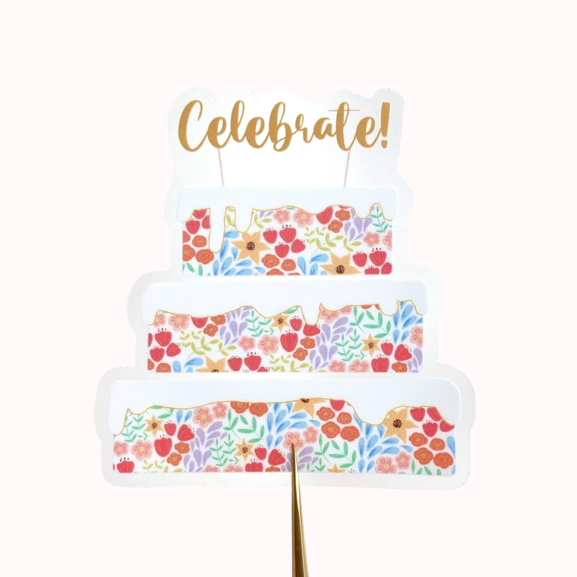 Decorative cake sticker with floral pattern and gold 'Celebrate!' text on a white background