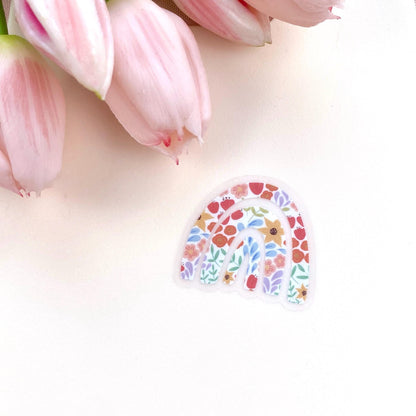 A rainbow shaped sticker with a colourful floral design on a white background with pink tulips.
