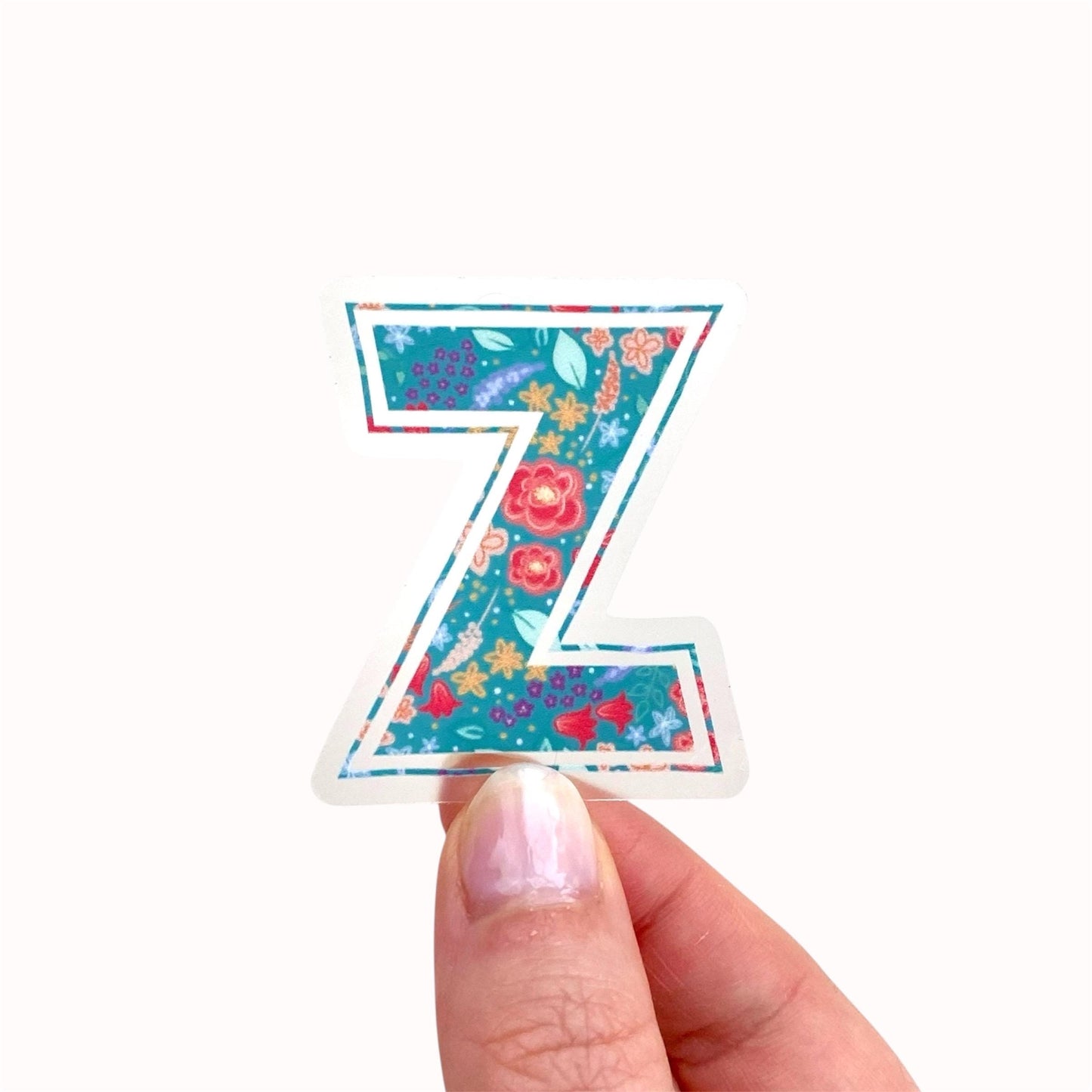 Decorative letter 'Z' sticker held by a hand on a white background
