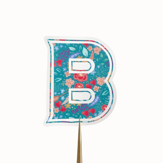 Clear sticker with a teal floral decorated letter 'B' against a cream background.