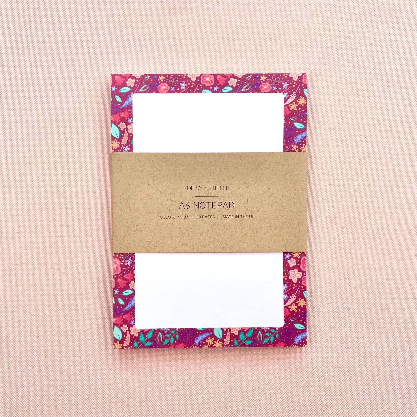 Floral notepad with a brown kraft cover on a pink background