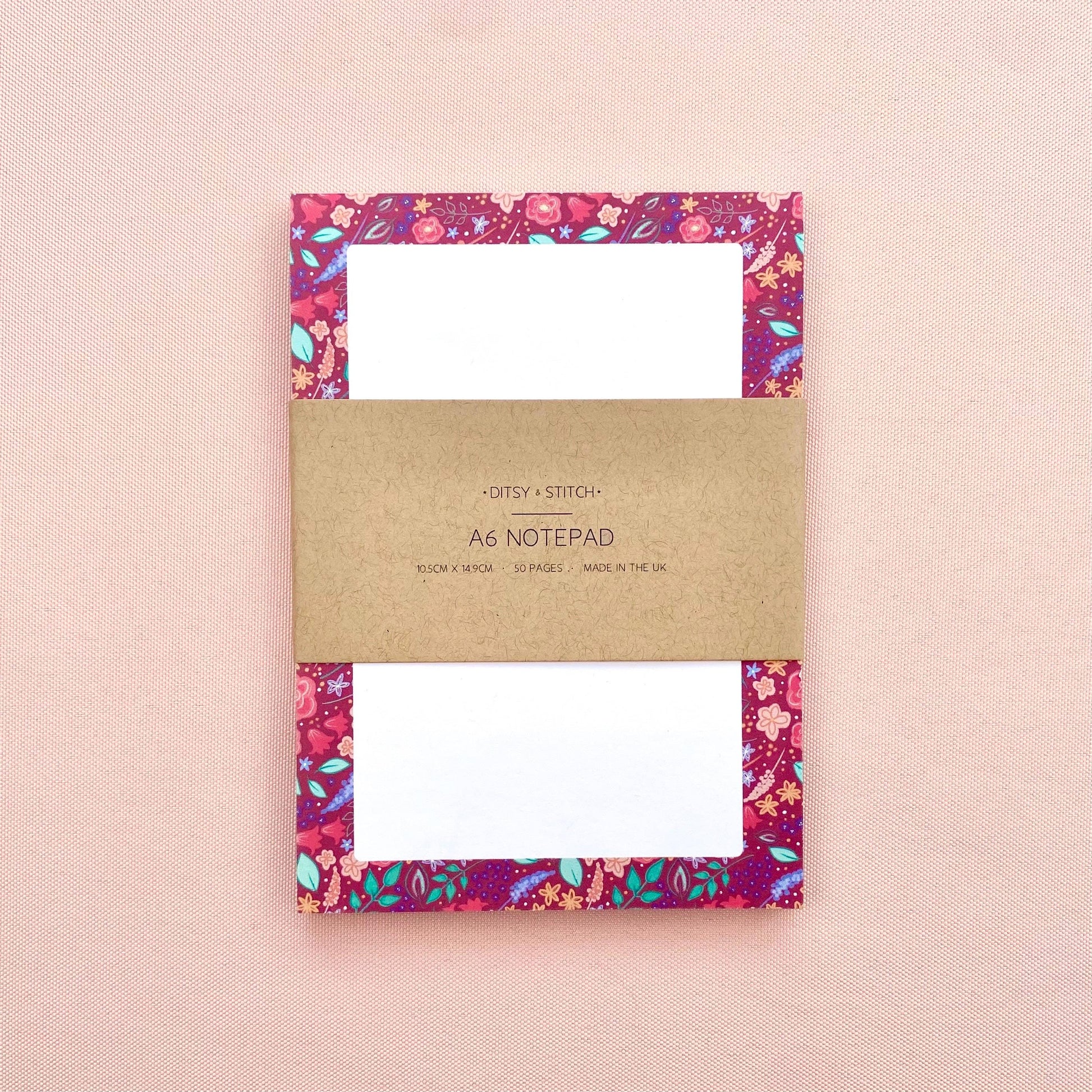 Floral notepad with a brown kraft cover on a pink background