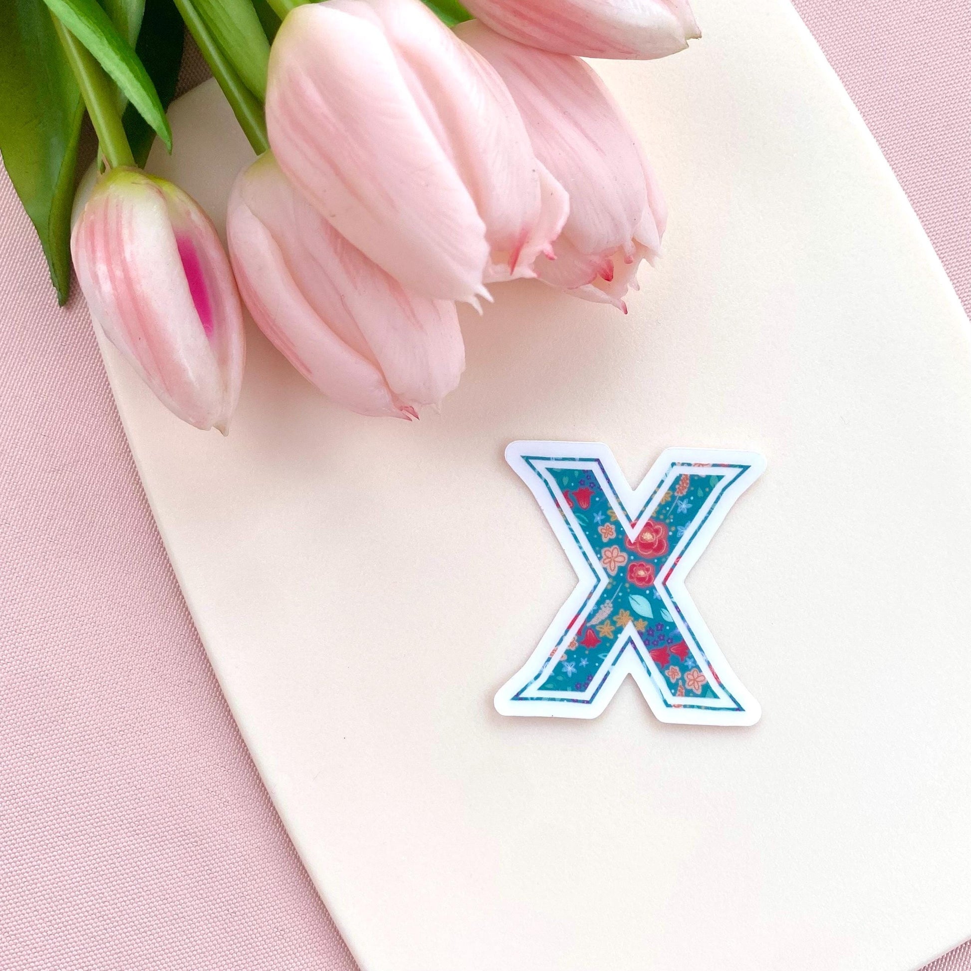 Letter 'X' sticker with pink tulips on a pink background