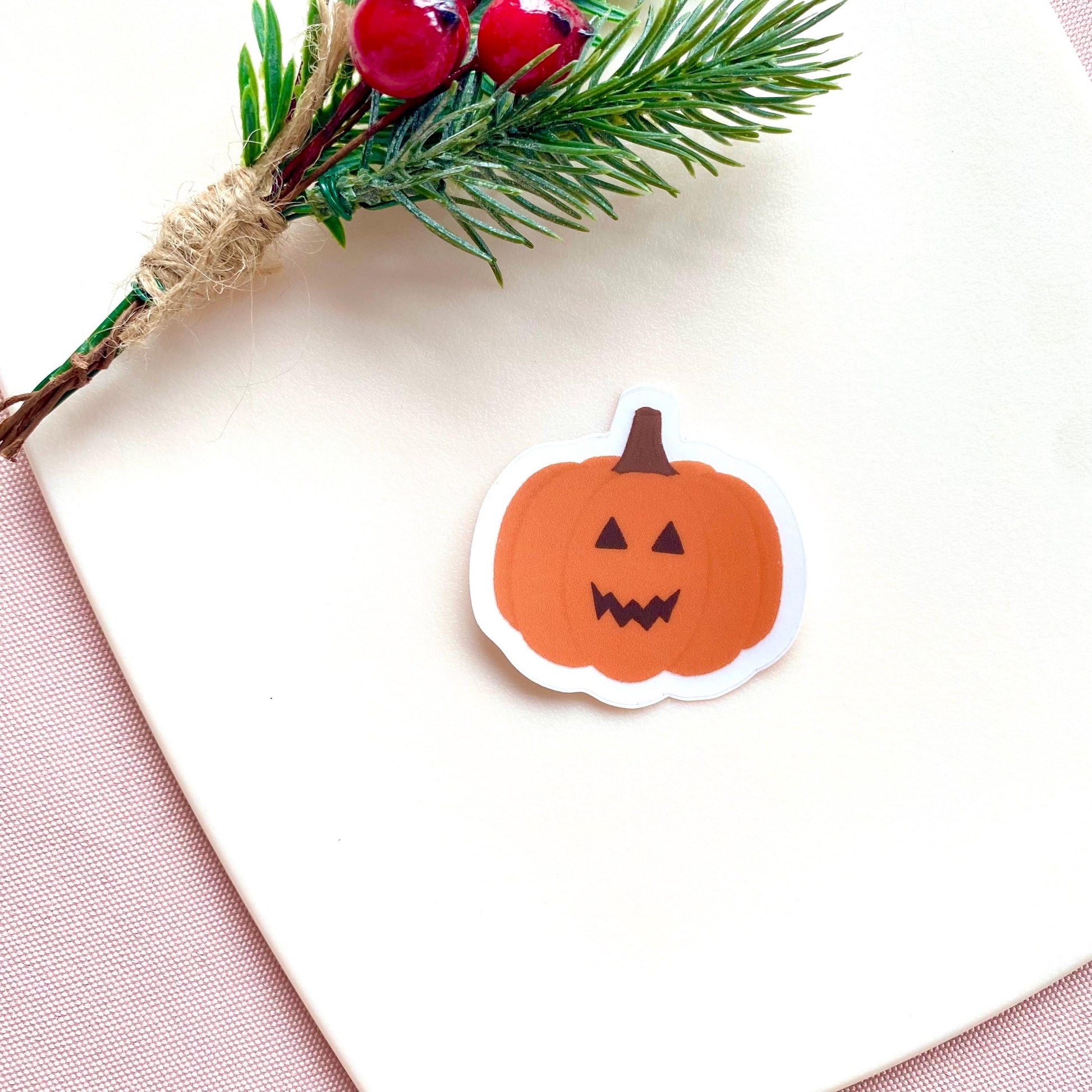 Orange jack-o-lantern pumpkin sticker against a pink background.