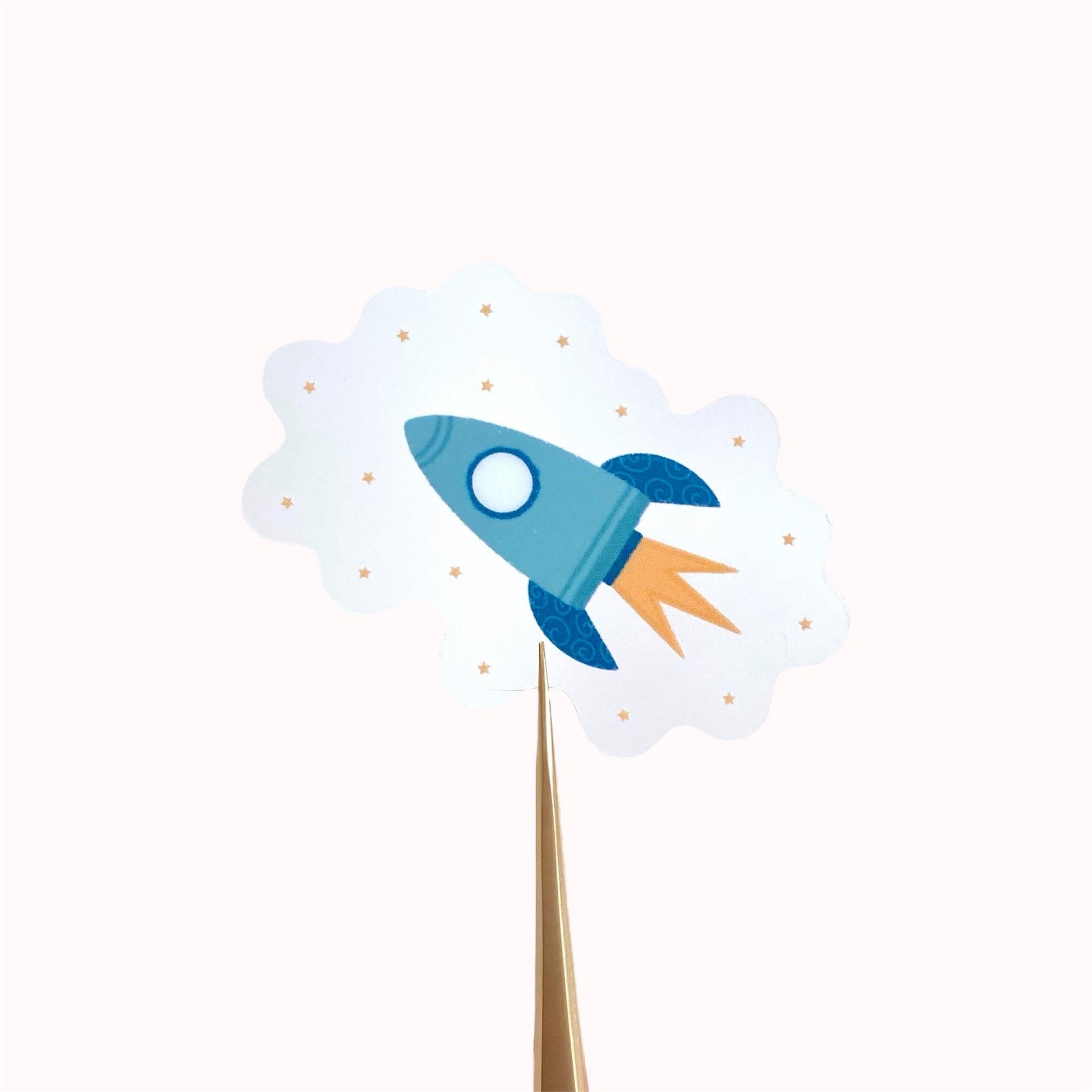 Transparent sticker with teal blue rocket against a cream background