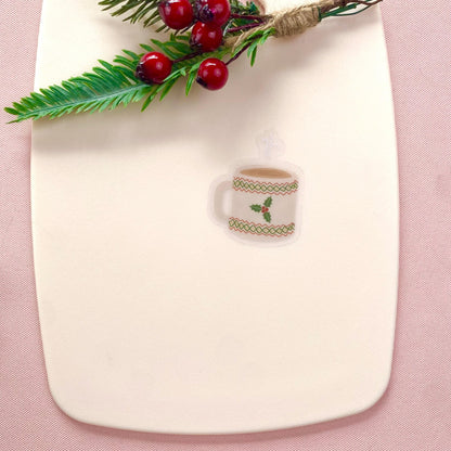 Sticker design of a mug with holly on a white fabric background