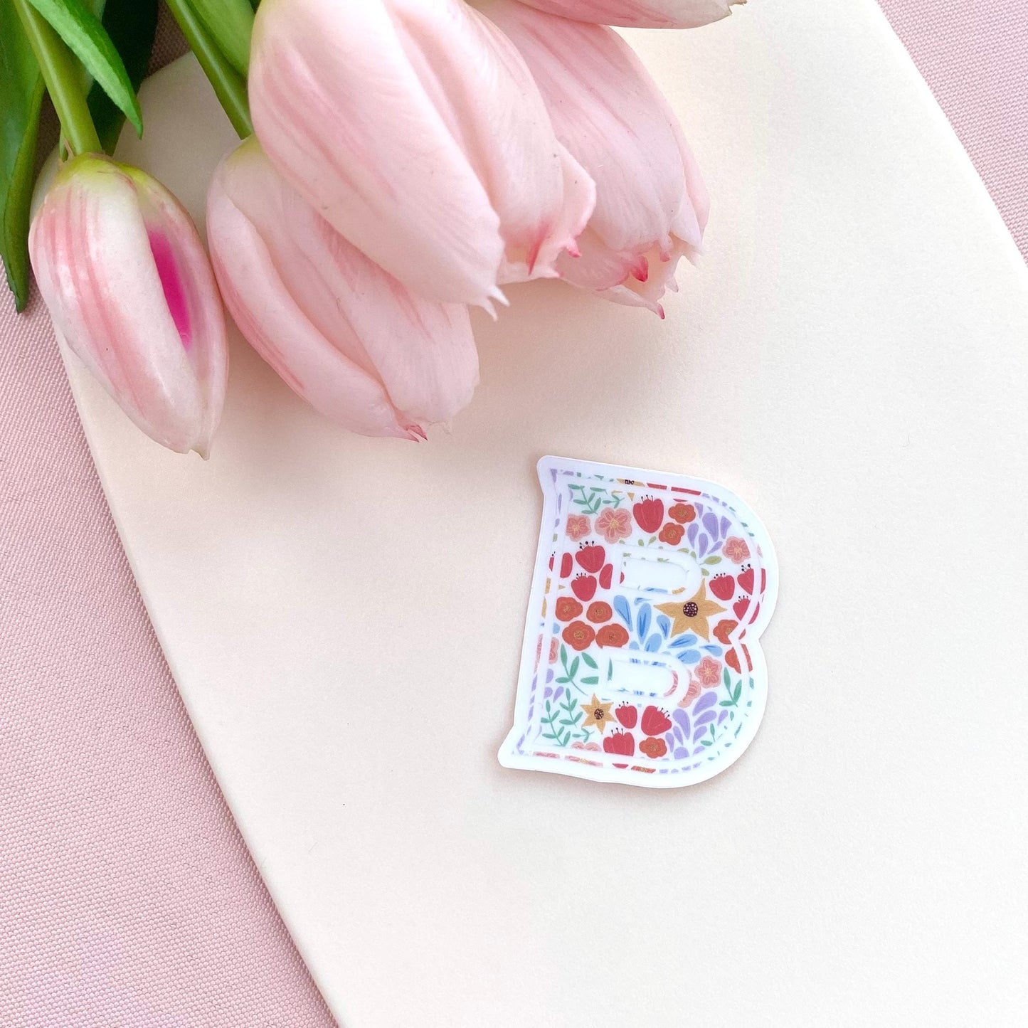 Floral letter 'B' sticker on a white surface with pink tulips.
