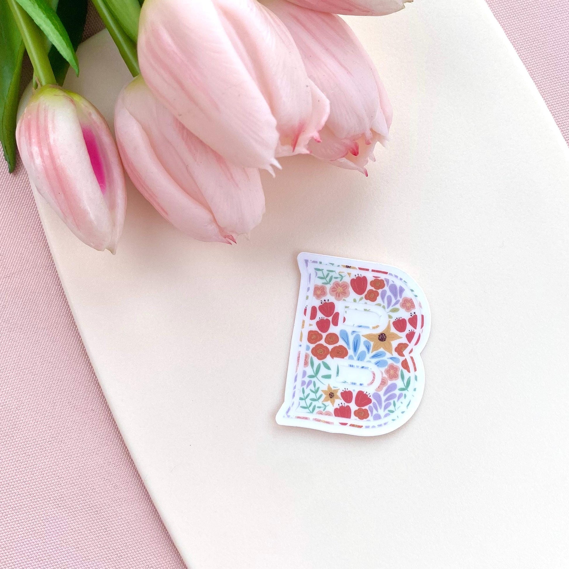 Floral letter 'B' sticker on a white surface with pink tulips.