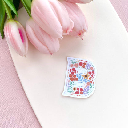 Floral letter 'B' sticker on a white surface with pink tulips.