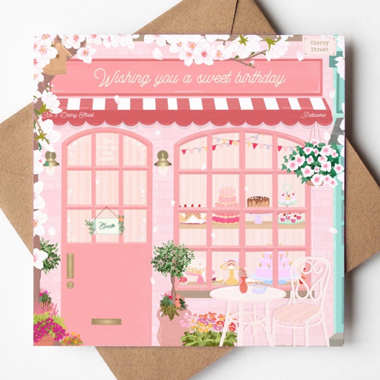 Card with a pink bakery illustration and 'Wishing you a sweet birthday' text on a brown envelope.