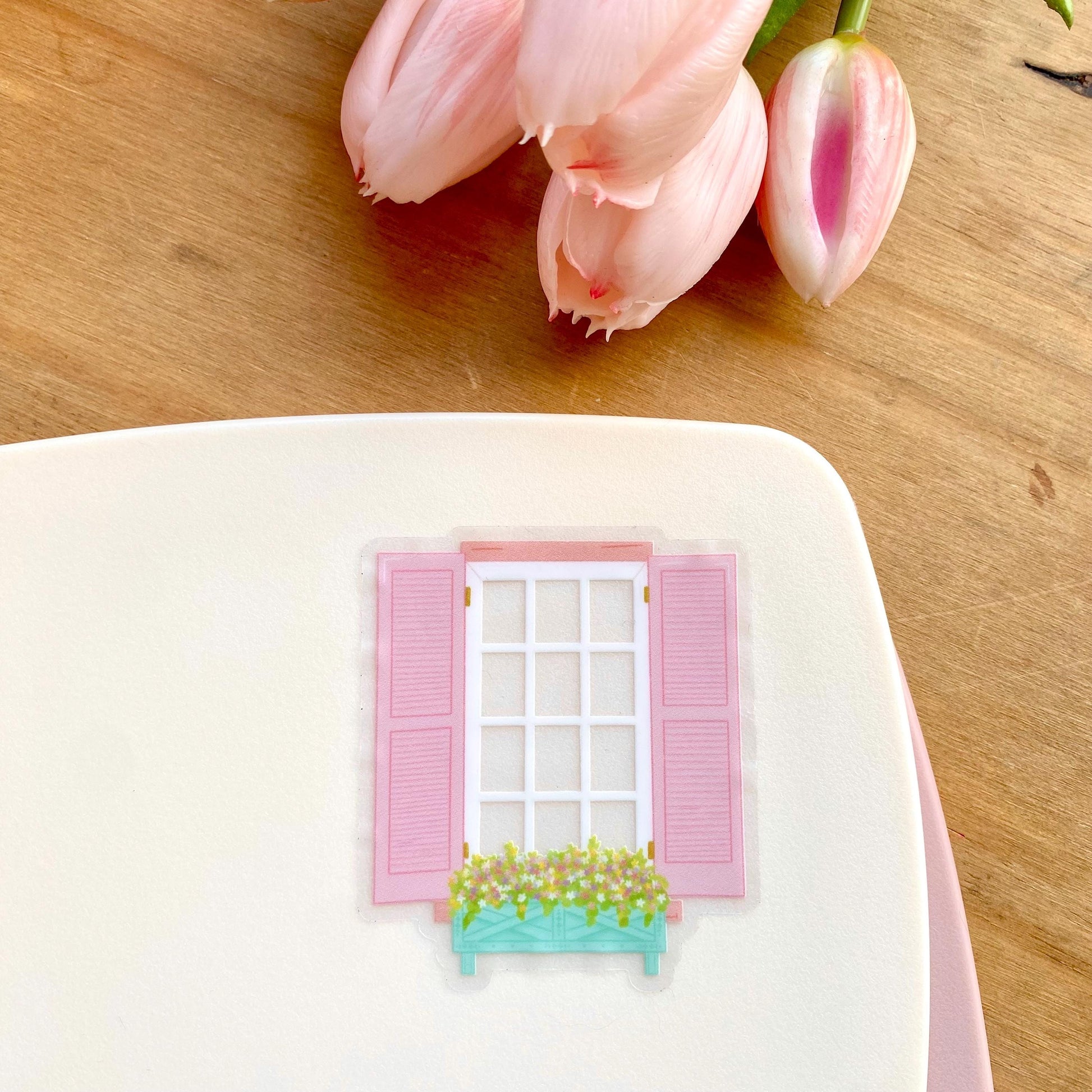 Transparent sticker of a window with pink shutters and a flower box on a white background
