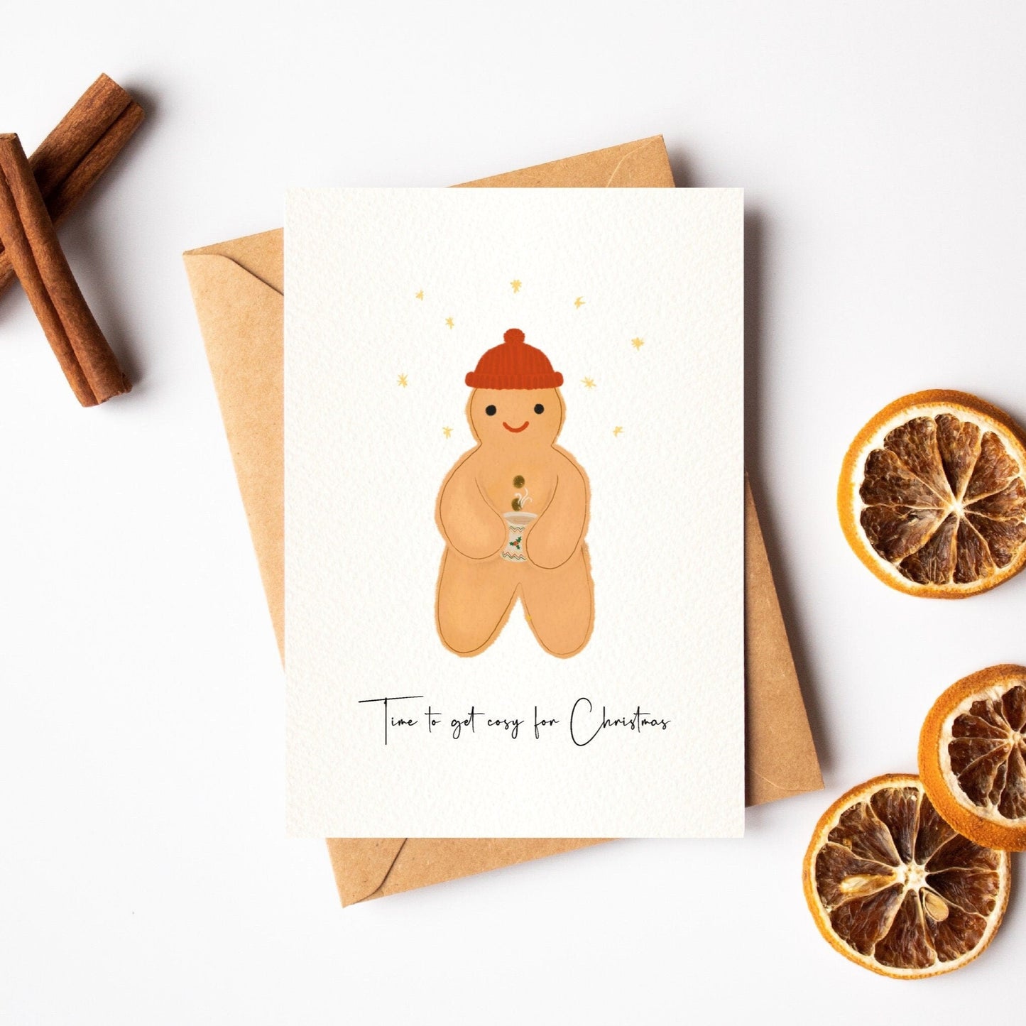Greeting card with a gingerbread man illustration, cinnamon sticks, and dried oranges on a white background