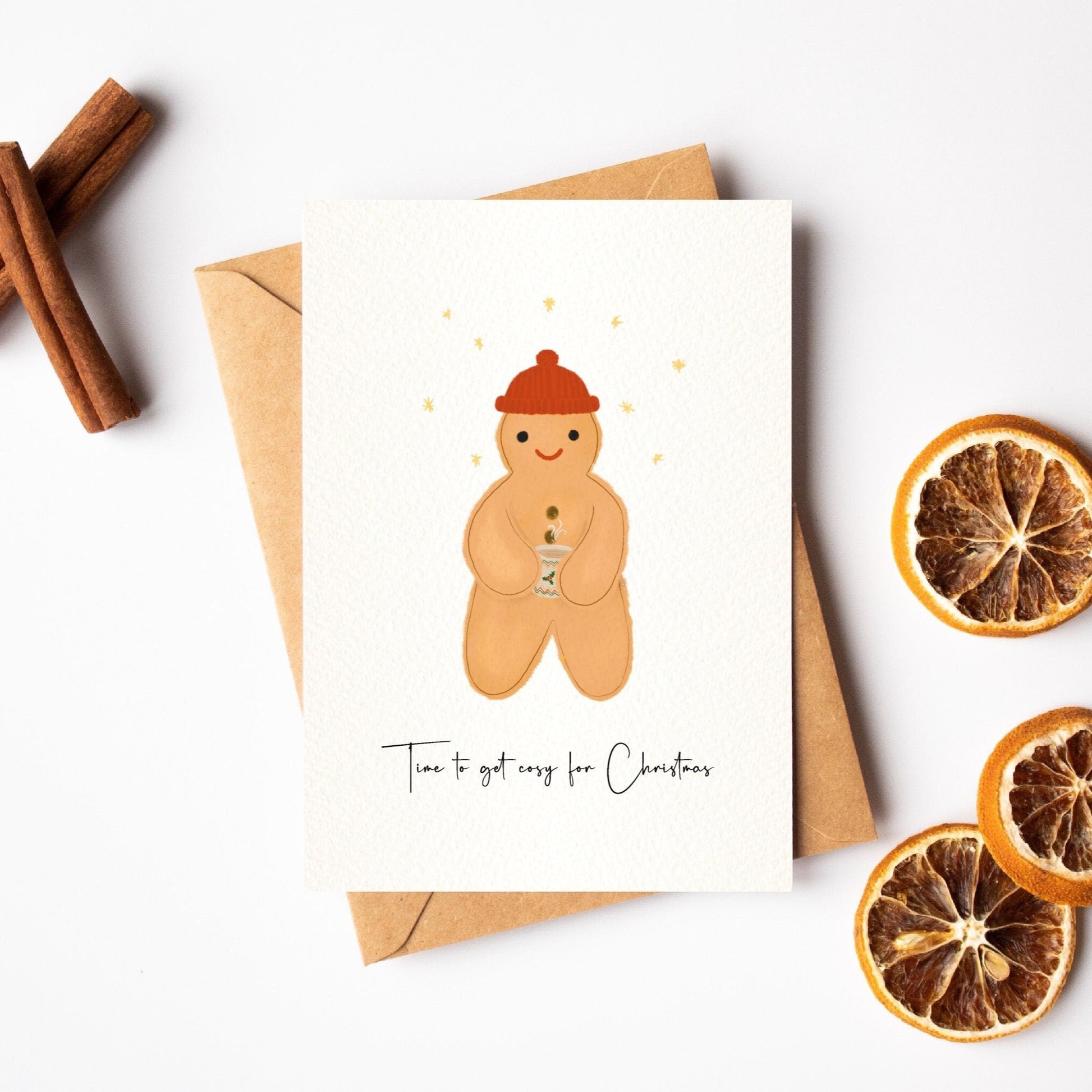 Greeting card with a gingerbread man illustration, cinnamon sticks, and dried oranges on a white background