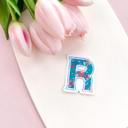 Floral letter 'R' sticker on a pink surface with tulips