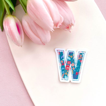 Floral letter 'W' sticker on a pink surface with tulips