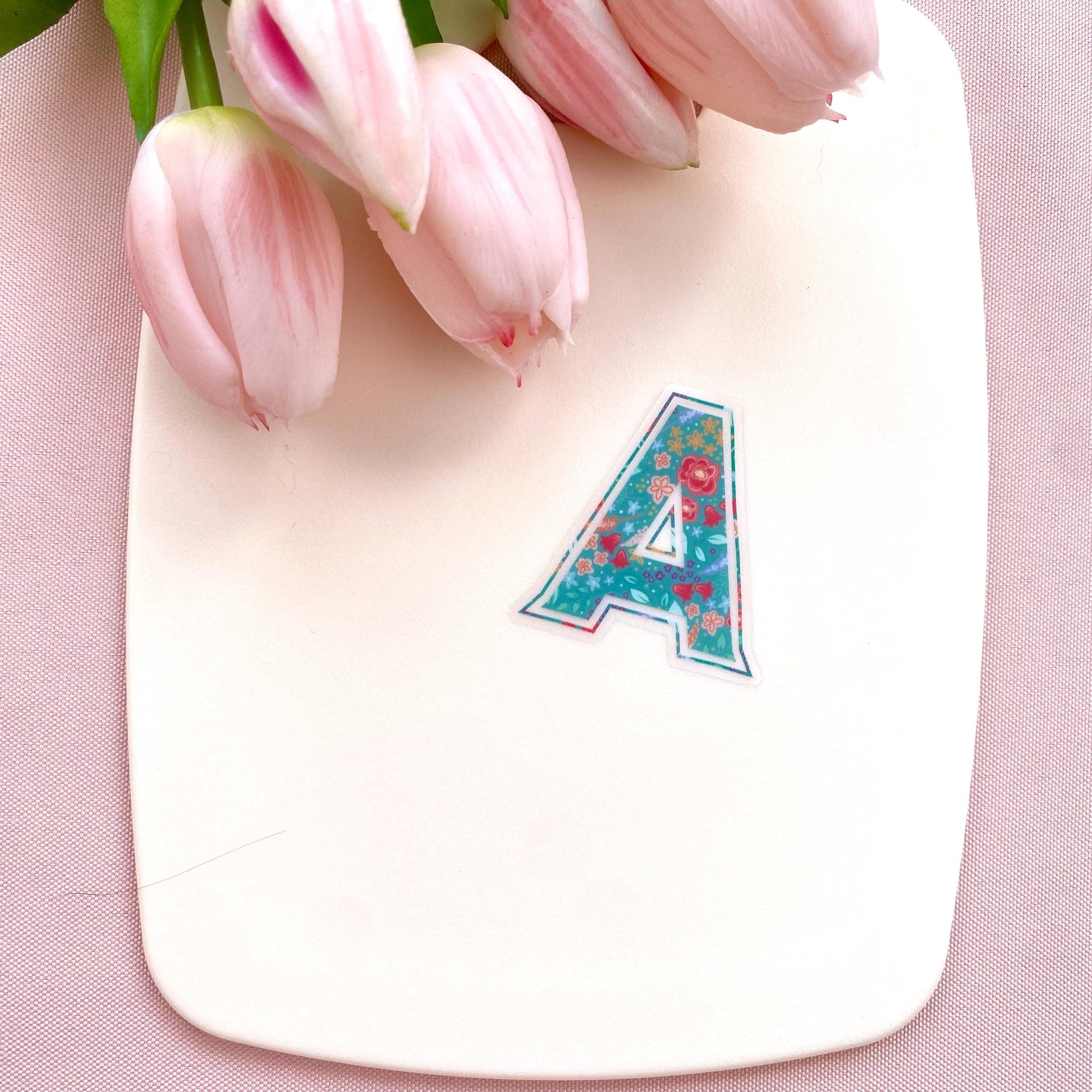 Letter 'A' sticker with floral design on a cream background with pink tulips.
