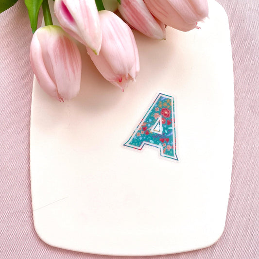 Letter 'A' sticker with floral design on a cream background with pink tulips.