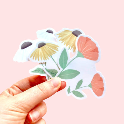 Hand holding floral stickers against a pink background