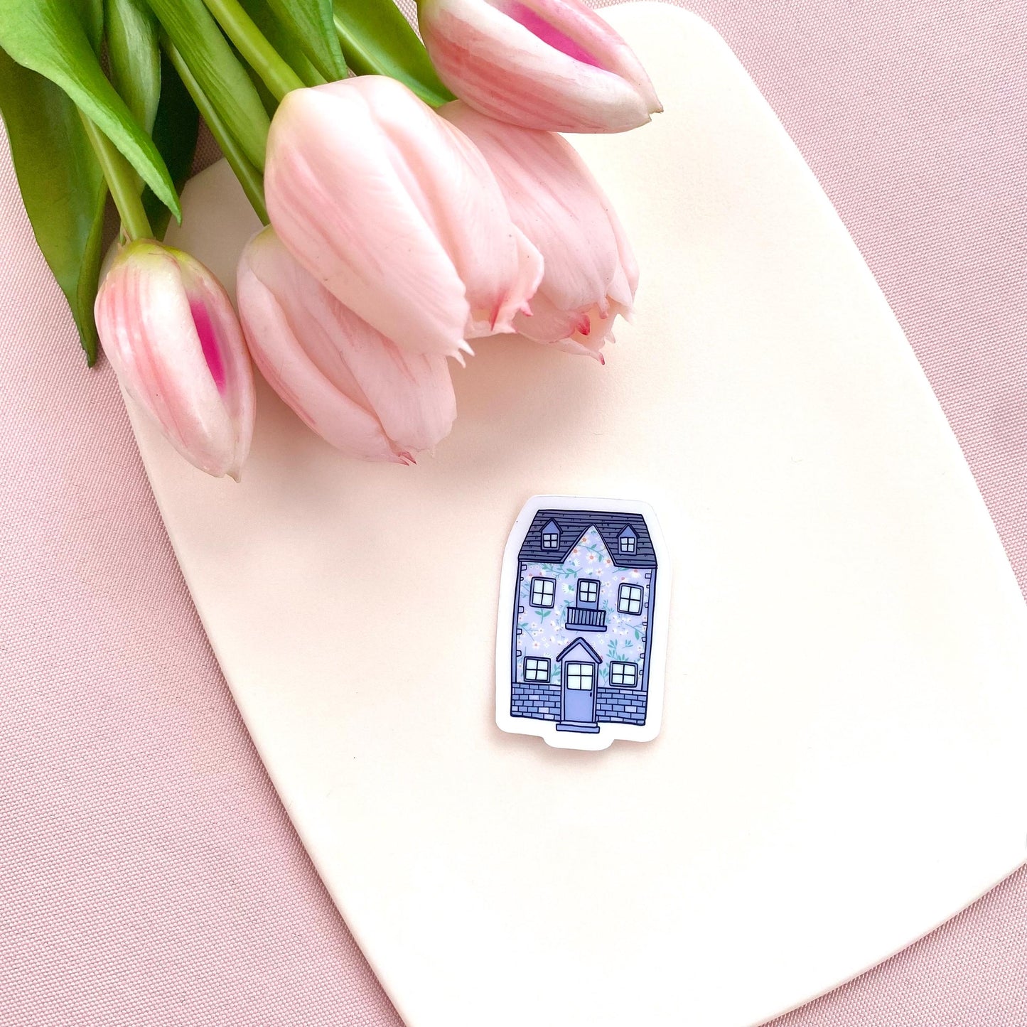 Blue floral patterned house sticker on a cream background with pink tulips.