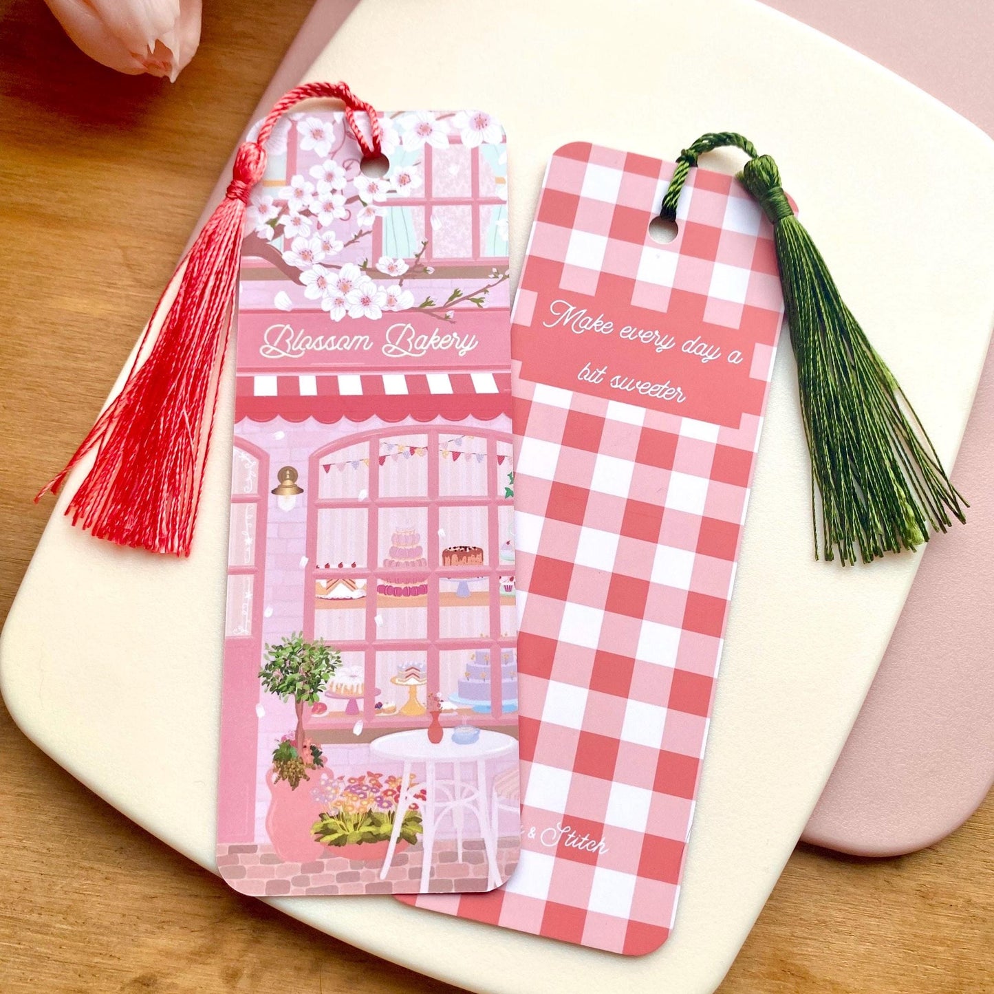 Two matching pink bookmarks with tassels on a white surface, one bookmark showing the front design and the other showing the back