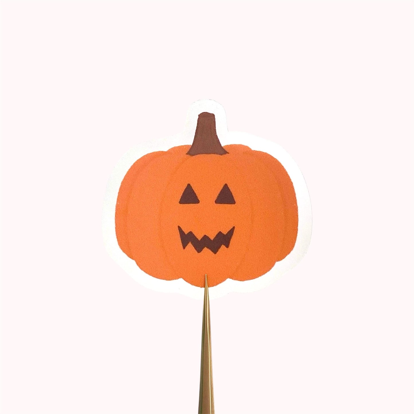 Orange jack-o-lantern pumpkin sticker held against a pink background.