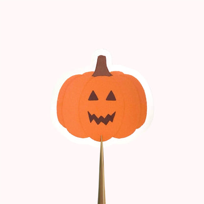 Orange jack-o-lantern pumpkin sticker held against a pink background.
