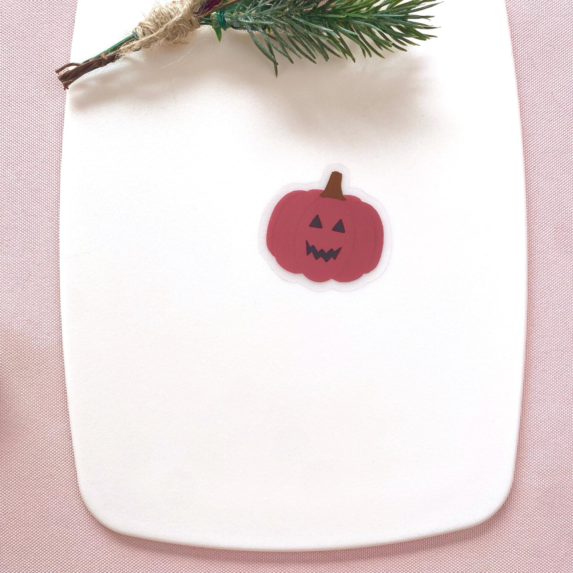 Pink pumpkin-shaped sticker on a white plate with a pink background