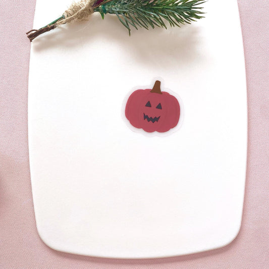 Pink pumpkin-shaped sticker on a white plate with a pink background