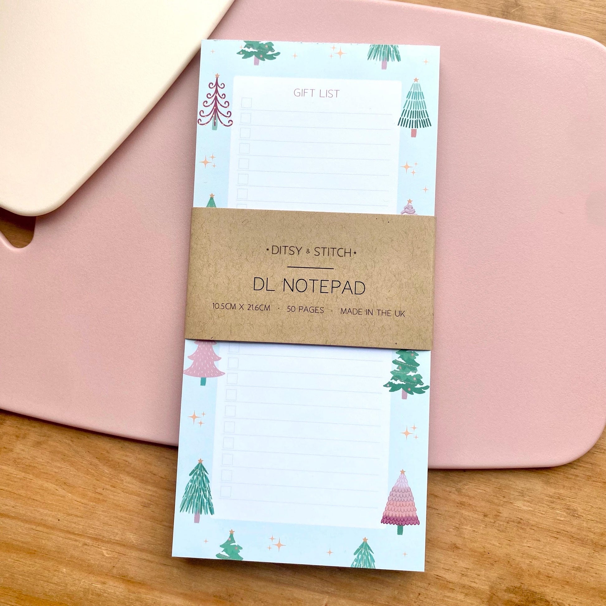 Notepad with Christmas tree design on a pink surface