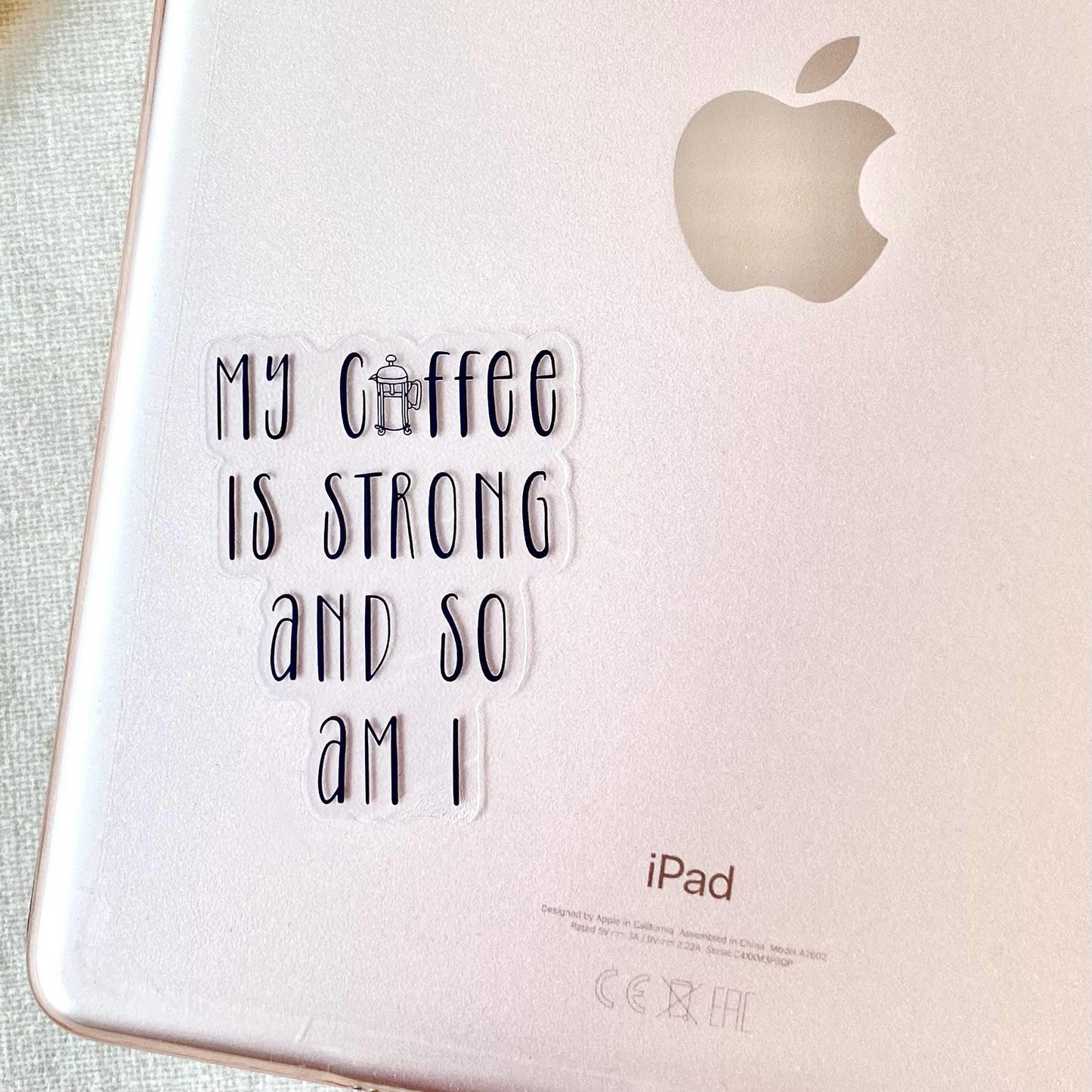 Rose gold iPad with 'My coffee is strong and so am I' sticker and Apple logo.