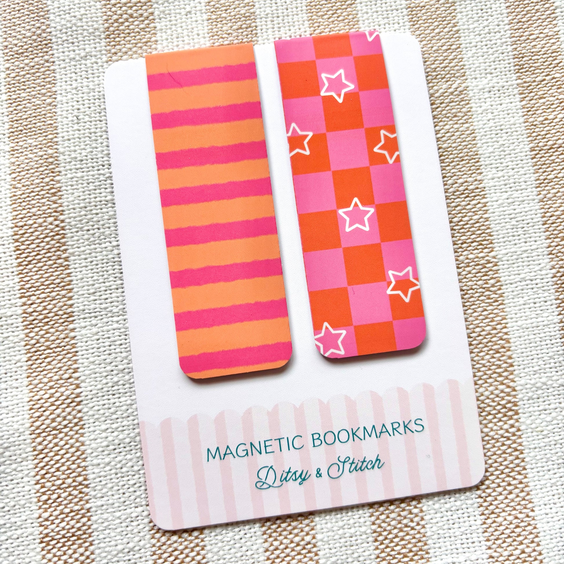 Two colourful magnetic bookmarks on a card with 'Ditsy & Stitch' branding, placed on a striped fabric background.