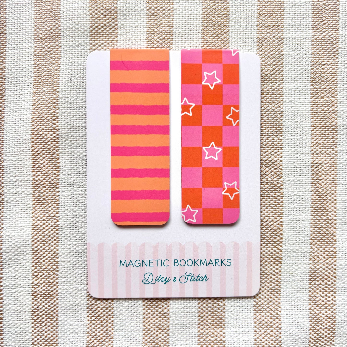 Two colourful magnetic bookmarks with pink and orange checkerboard and striped patterns on a card with 'Ditsy & Stitch' branding against a striped background.